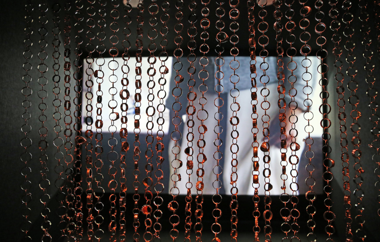 Curtain of wedding rings with video image of people behind it