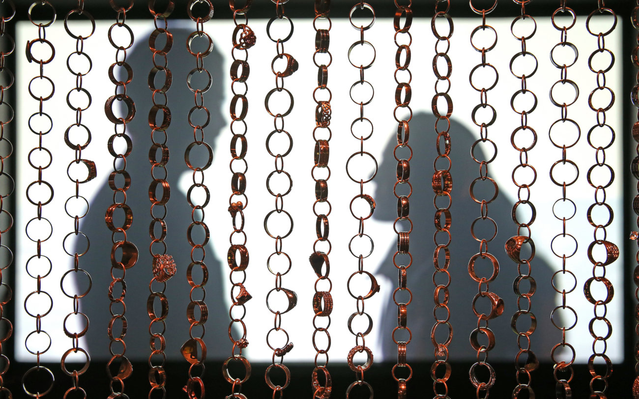 Curtain of wedding rings with video image of two people behind it