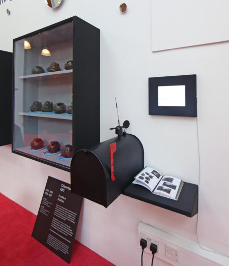 Gallery install photo of display on walls with US postbox style object